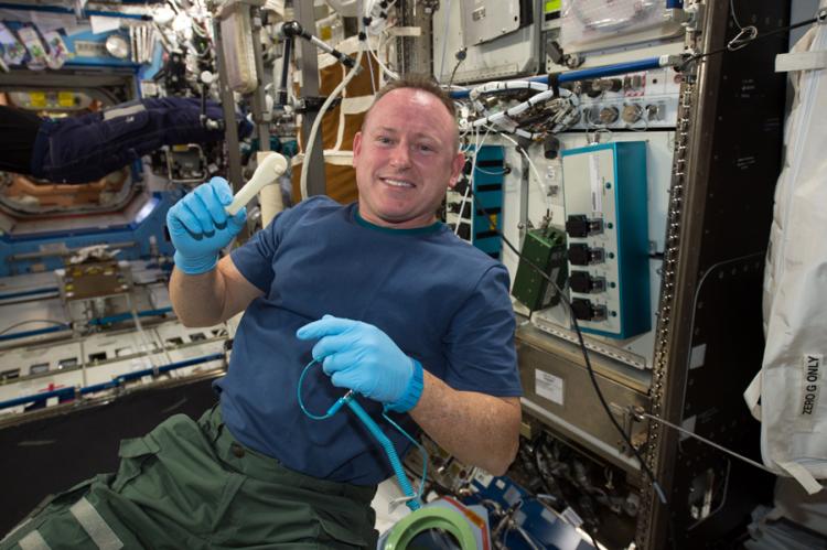 Astronaut in space station shows plastic 3-D printed ratchet wrench.