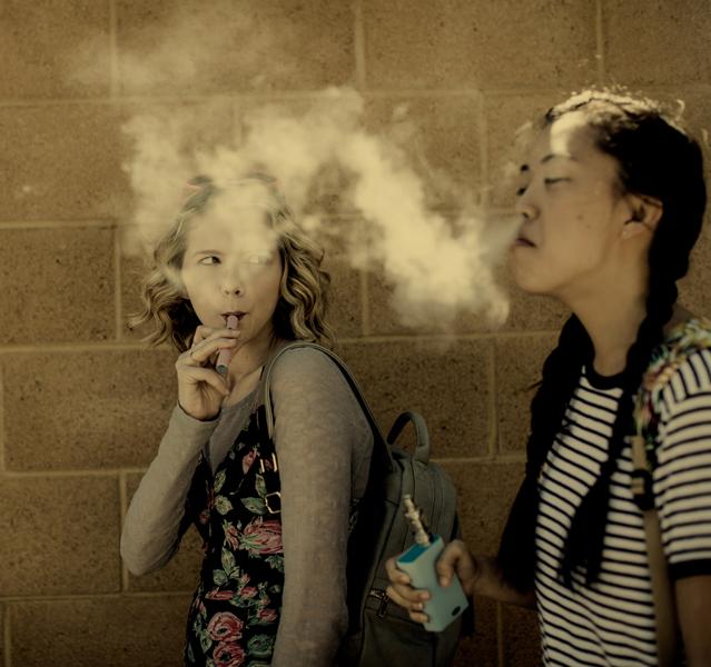 Two school girls vaping in a cloud of smoke