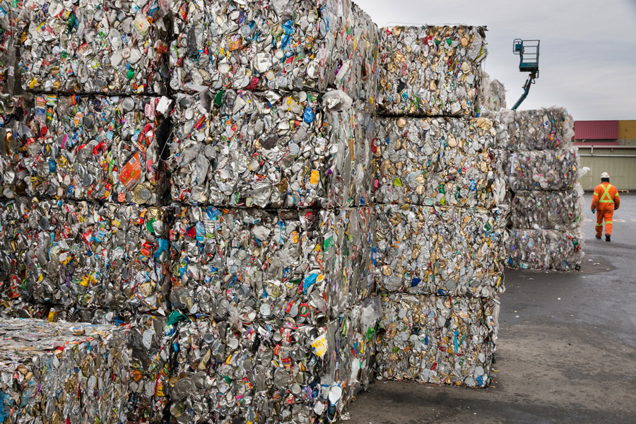 Photo shows a large cube made of compacted recycled tin cans.