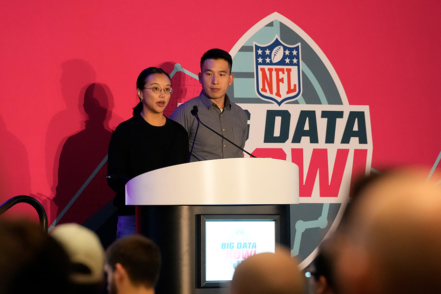 Katherine Dai and Matt Chang stand at a podium with an NFL Big Data Bowl sign in the background