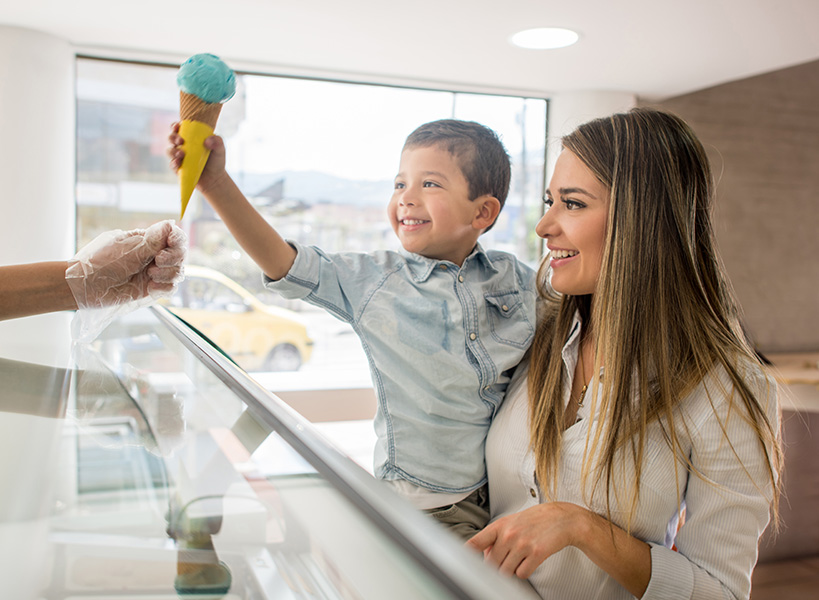 Happiness and food A happy child in his mother’s arms takes an ice cream cone.