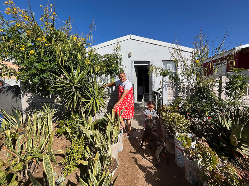 Maria Photograph of a woman in a red dress standing in her yard.